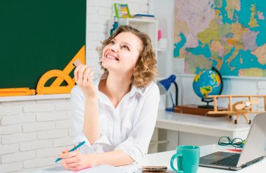 Öğretmen Lider. Öğrenci sınıfta ders çalışıyor. Modern öğretmen hipster okulda öğretmenlik yapıyor. Kütüphanedeki bir kitaptan notlar alan kız öğrenci.