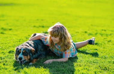 Çocuk dışarıda köpeğe sarılıyor. Çocuk evcil köpeğini sevgiyle kucaklıyor. Yavru köpeği olan sevimli bir çocuk, açık hava yazı.