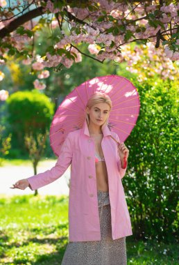 Çiçek açan sakura ağacının yanında poz veren iki güzel, modaya uygun genç bayanın açık hava portresi. Bahar aksesuarları ve giysileri. Kadın güzelliği ve moda. Şehir yaşam tarzı.