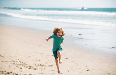 Çocuk yaz kumsalında koşup zıplıyor.