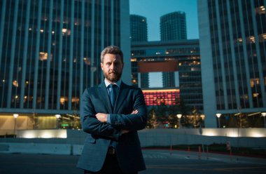 Ofisin dışında duran kendinden emin bir iş adamının portresi. İş yerinin dışında kolları kavuşturulmuş gülümseyen iş adamı CEO 'su. İyi giyimli iş adamı.