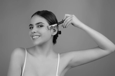 Kadın makyaj fırçası kullanarak yüzüne pudra sürüyor. Yanaklarına allık süren bir kız. Güzellik kozmetikleriyle yüzleş. Taze ten ve doğal makyaj. Yüz derisinde pudra lekesi