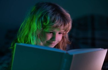 Kitap okuyan şirin bir çocuk. Açık kitabı olan bir çocuk. Ev okulu dersi. Evde kitap okumaya odaklanmış küçük bir çocuk. Hayal gücü ya da öğrenme kavramı