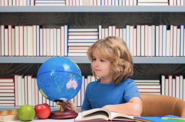İlkokulun kütüphanesindeki küreye bakan bir öğrenci. İnek okulu çocuğu. İlkokuldan zeki bir çocuk. Zeki dahi zeki çocuk öğrenmeye hazır. Dünya küresi
