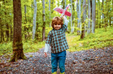 Uçma hayalleri. Çocuk gökyüzüne karşı oyuncak uçakla oynuyor. Seyahat hayalleri. Oyuncak uçağı olan rüya gören küçük çocuk dışarıda oynuyor.