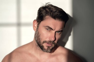 Kozmetik, vücut bakımı ve spa tedavisi. Beyaz arka planda izole edilmiş erkeksi, çekici, üstsüz bir adam portresi. Çekici adamın yakın plan portresi.