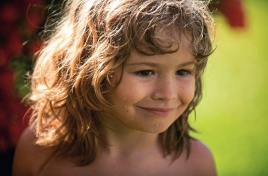 Çocuk portresi doğada, parkta ya da dışarıda. Yazlık parkta oynayan mutlu çocuğun yüzünü kapat.