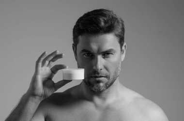 Yüz kremi süren yakışıklı yaşlı bir adam. Güzellik rutini. Mükemmel ciltli bir adam. Yaşlanma önleyici ve kırışıklık önleyici krem. Erkek güzelliği kavramı. Cilde krem süren adamın yüzünü kapat. Cilt bakımı ve kozmetik