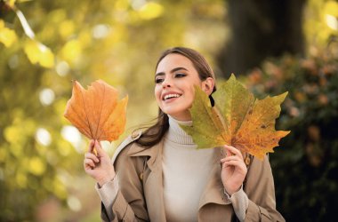 Yaprakları olan sonbahar aşkı kadını. Yeşillik gününde kadın model. Hayal ve yaşam tarzı. Güzel bir açık hava portresi. Kaygısız, muhteşem, duygusal, çekici, yüzünde yaprak olan bir kız. Sonbahar doğası