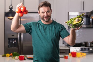 Modern mutfakta tek başına sağlıklı yemekler hazırlayan, salata pişiren bir adam. Yakışıklı adam evdeki mutfakta taze vegan salatası hazırlıyor. Sağlıklı yemek sağlıklı hayattır.