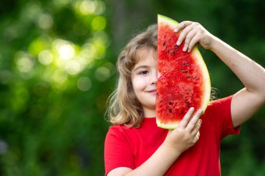 Karpuzlu şirin çocuk. Yazlık parkta karpuz yiyen komik çocuk. Çocuk, bebek, sağlıklı yemek. Bahçede karpuz yiyen bir çocuk. Çocuklar dışarıda meyve yer. Çocuk karpuz seviyor.