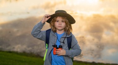 Çocuk keşif konsepti. Dürbünlü çocuk doğa yürüyüşü yapıyor. Küçük kaşif. Çocuklarla açık hava eğlencesi ve maceralar. Güneşli kırsal kesimde çocuk turist