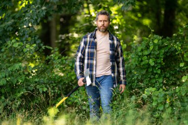 Kendine güvenen oduncu yaz ormanlarında çalışıyor. Baltalı adam. Ormanda ekose gömlekli bir oduncu. Baltalı hippi. Baltalı oduncu. Sakallı oduncu. Baltalı Amerikalı oduncu.