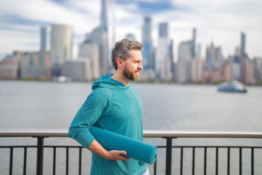 Spor salonundaki adam Manhattan yakınlarında egzersiz yapıyor. Sağlıklı fitness yaşam tarzı. Aktif kıdemli adam dışarıda fitness egzersizi yapıyor. Emeklilikten sonra spor. Olgun emekli sporcu esneme egzersizleri yapıyor.