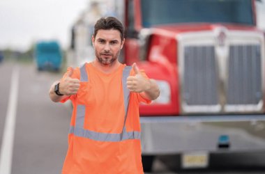 Kamyonun yanında erkek sürücü var. Kamyonetin yanında güvenlik yeleği giyen bir kamyon şoförü var. Yakışıklı, orta yaşlı kamyoncu kamyoncu adam. Ulaşım endüstrisi araçları. Kamyonun önündeki yakışıklı adam.