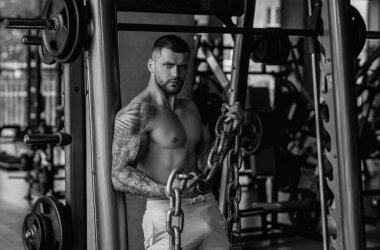 Ağırlık metal zincirlerle egzersiz yapan bir adam. Uygun model ağırlık kaldırma zinciri, spor salonunda egzersiz. Zincirlerle çalış. Güçlü, kaslı, formda, zincirleri ve ağır ağırlığı olan bir adam. Pazılar için alıştırmalar