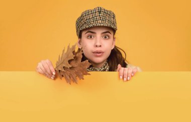 Sonbahar kadını, izole edilmiş stüdyo portresi. Sonbahar yaprakları olan komik bir genç kız. Sarı arka planda sonbahar şapkası ve atkısı olan güzel bir kız. Poster tahtası tasarımı