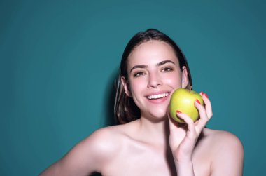 Elmalı insanlar. Stüdyonun arka planında elma yiyen genç bir kadının portresi. Doğal vitamin, diyet ve sağlıklı yaşam için sağlıklı elma meyvesi. Stüdyo resmindeki kadın yeşil elma yiyor.