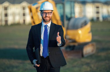 İnşaat mühendisi ya da inşaat mühendisi. İnşaat alanında kask ve takım elbiseli mühendis. Kazıcının yanındaki inşaat müdürü. Yenileme konsepti