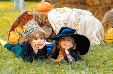 Cadılar Bayramı partisi için iskelet ve cadı gibi giyinmiş balkabaklı çocuklar. Mutlu Cadılar Bayramı Çocuklar Kız ve Oğlan sonbaharda samanlıkta ya da samanlıkta oturur