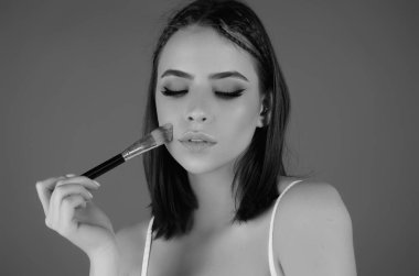 Woman applying foundation powder or blush with makeup brush. Facial treatment, perfect skin, natural make up, facial beauty. Isolated on studio background. Applying makeup