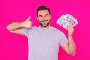 Orta yaşlı İspanyol adam, izole edilmiş pembe arka planda nakit para tutuyor. Dolar banknotları olan bir iş adamının stüdyo portresi. Dolar parası konsepti. Kariyer zenginliği işi