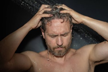 Milenyum adamı banyoda saç yıkıyor. Küvette banyo yapan adam. Yüzü duşta köpüklü. Banyo yapan adam duş alıyor. Yakından duş alan adam. Duş konsepti. İnsan duşta su altındadır.