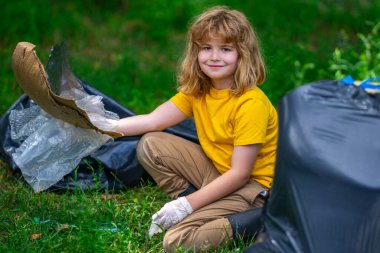 Küresel çevre kirliliği. Çocuk dışarıda plastik çöp topluyor. Çevre koruma kavramı. Çocuk çöp torbasına atık koyuyor. Eko çocuklar gönüllü. Çevre kirliliği
