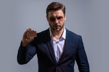 Gri arka planda kredi kartı olan bir adamın stüdyo portresi. Para yönetimi ve kredi puanı. Ödül parası. Kredi limiti. İnternetten alışveriş konsepti. Kredi geçmişi. Finansal sorumluluk