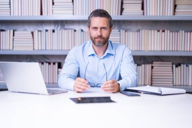 Sınıfta kitabı olan bir öğretmenin portresi. Sınıfta yakışıklı bir öğretmen. Öğretmenler Günü. İyi bir öğretmen. Sınıfta öğretmen. Sınıfta kitapları olan bir adam. Bilgi ve eğitim kavramı