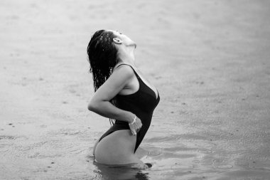 Seksi yaz tatili. Mayolu güzel bir kız suda seksi poz veriyor. Seksi bronzlaşmış vücut, mükemmel vücut. Doğal olarak dinlen. Suda poz veren seksi bir model, açık hava portresi. Bikini modeli