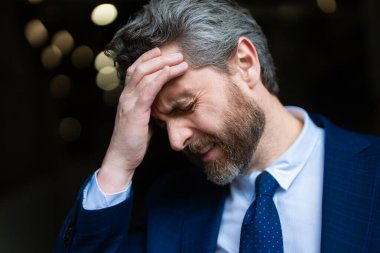 Üzgün iş adamının migreni tuttu. Güçlü baş ağrısı olan bir adam. Stresli, baş ağrısından yorgun iş adamı. Baş ağrısı, yorgunluk ve stres, migren. Baş ağrısı konsepti