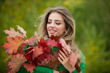 Sarı akçaağaç yaprağıyla sonbahar kadını, açık hava portresi. Sonbahar yapraklı güzel bir model, sonbahar parkında sarı akçaağaç. Sonbahar kızı sonbahar mevsiminde güneşli havanın tadını çıkarıyor.