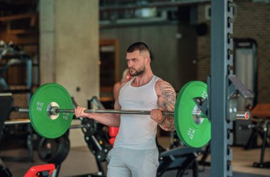 Handsome fit muscular caucasian man workout in the gym with weight pumping up muscles. Fitness and bodybuilding sport. Bodybuilder with dumbbells at gym, hard workout