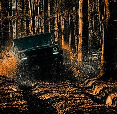 Off-road yarışında çamur ve su sıçraması. Çamur çukurundan çıkan off-road aracı. Timud ve su yarışın dışına sıçrıyor. Sürüklenen yarış arabası lastik yakar. Aşırıya kaçmış. Off-road arabası