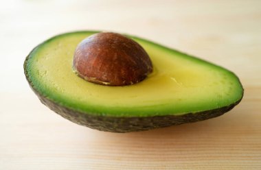 Ahşap arka planda avokado. Avokado meyvesi. Çiğ meyveler sağlıklı yeşil yiyecekler. Tam ve yarım avokado.