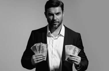 Başarılı bir iş adamı para sayıyor. Yakışıklı orta yaşlı adam 100 dolarlık banknotları tutuyor. Elinde para tutan adam. Kâr ve finansal başarı. Dolar nakiti olan zengin bir adam.