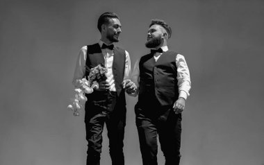 Gay grooms walking together on Wedding day. Gay man groom at wedding. Happy male gay couple with flowers holding hands on wedding. Romantic and sensual gay couple clipart