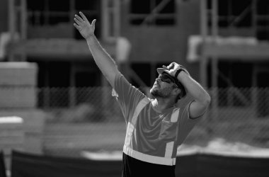 İnşaatta çalışan işçi. Kasklı inşaat işçisi dışarıda çalışıyor. İnşaat işçisi inşaat alanında çalışıyor. İşçi işaret ediyor