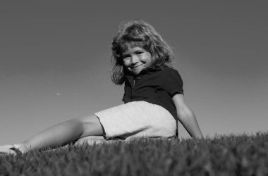 Yeşil çimlerin üzerinde yatan gülümseyen bir çocuğun portresi. Doğanın tadını çıkaran sevimli bir çocuk. Yaz parkında oynayan kaygısız sağlıklı bir çocuk. Sağlıklı çocuklar açık hava yaşam tarzı konsepti