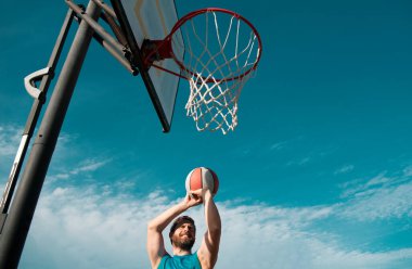 Güneşli bir günde dışarıda basketbol oynayan sporcular.