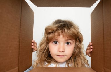 Mutlu küçük çocuk hediyesini açıyor ve karton kutunun içine bakıyor. Paketler ve teslimat