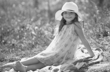 Küçük kız yaz parkında yeşil çimlerin üzerinde oturuyor. Komik çocuk duyguları. Açık havada, dışarıda oynayan sevimli küçük bir çocuğun portresi. Dışarıdaki güzel çocukların portresi.