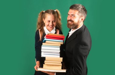 Baba, öğrenci kızını okula götürüyor. Modern aile babasının portresi ve yeşil karatahtaya izole edilmiş küçük kızlar. Elinde kitap yığını olan küçük bir kız. Çalışması zor.