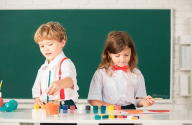 School children drawing a colorful pictures with pencil crayons in classroom. Portrait of cute pupils enjoying art and craft lesson clipart