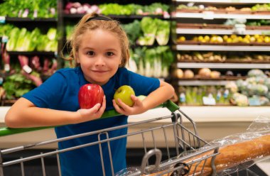 Marketteki elma meyveli çocuk. Markette ya da süpermarkette bir çocuk. Küçük çocuk alışverişe gidiyor. Çocuklar için sağlıklı yiyecekler