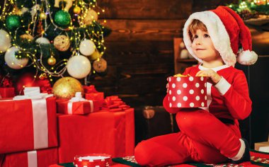 Çocuk Noel Baba kıyafetleri giyiyor, yeni yılı bekliyor. Çocuklar için Noel hediyeleri