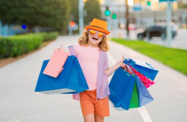 İndirim ve satış. Alışveriş torbalı mutlu çocuk. Küçük çocuk alışverişe çıktı. Moda ve markalar. Heyecanlı küçük alıcı.
