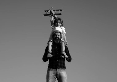 Çocuk babasının omuzlarında oturuyor. Çocuk oğlu pilot ve baba babası uçakla