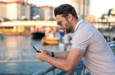 Şehir caddesinde telefonda konuşan yakışıklı bir adam. Büyük şehirde şehir hayatı yaşayan başarılı bir erkek model telefonda konuşuyor. Genç erkek manken dışarıda telefon kullanıyor. İş telefonu görüşmesi